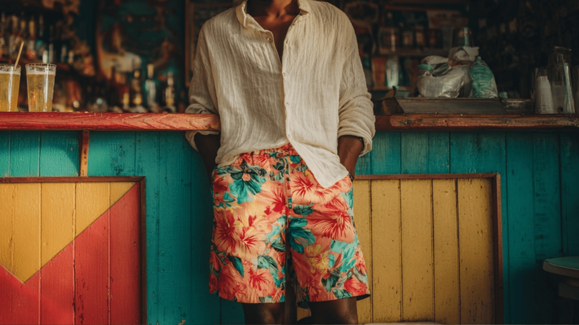 Man wearing tropical printed shorts with a plain t shirt for a stylish beach vacation outfit.