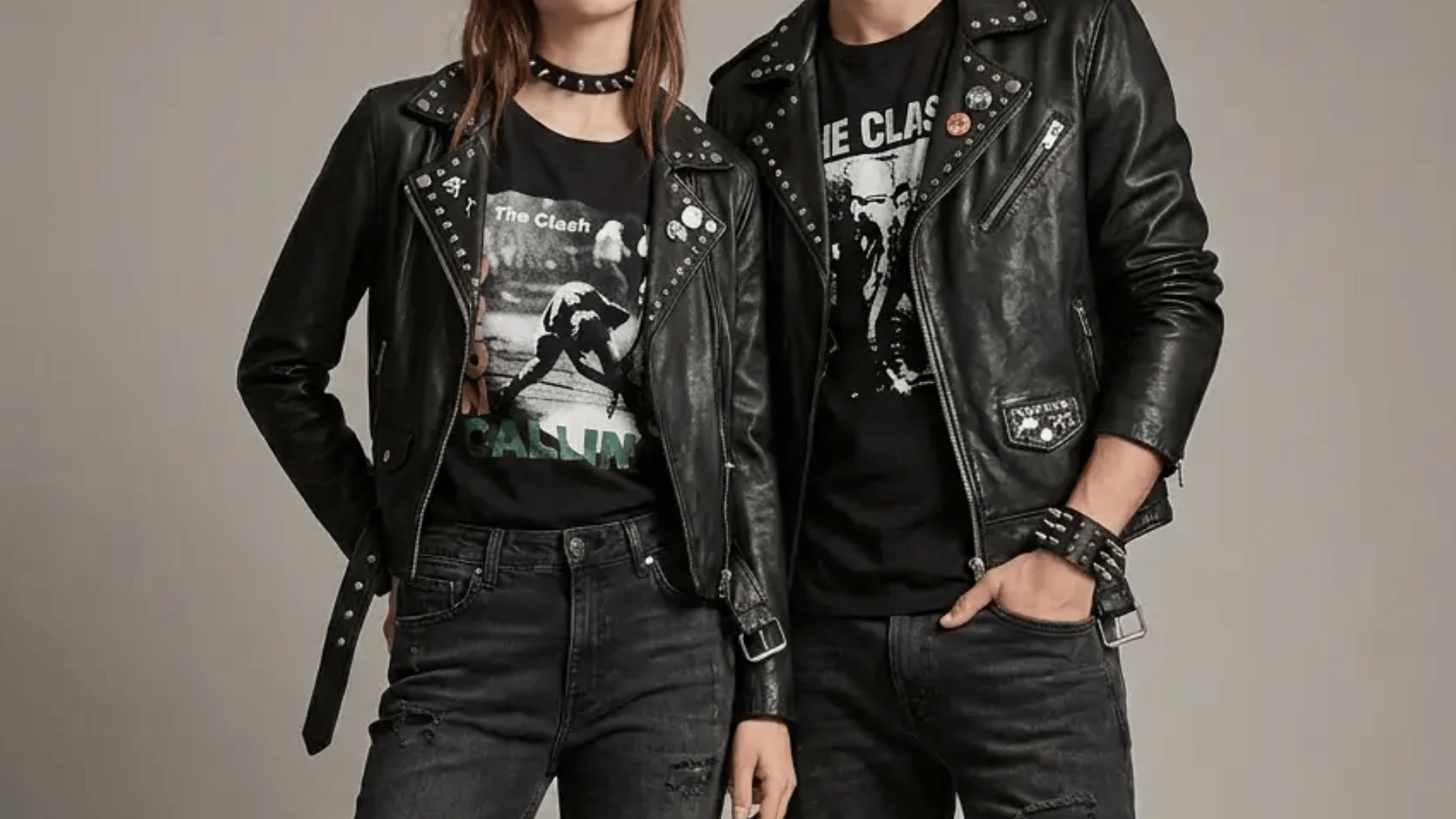 Couple in coordinated punk outfits, matching band tees, leather jackets, ripped denim, boots, and spiked jewelry, studio shot