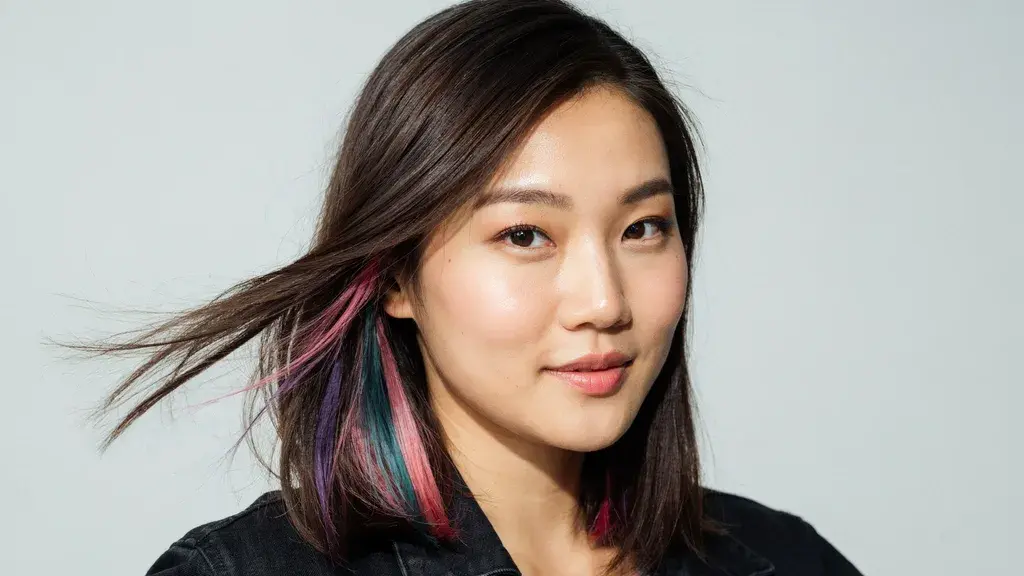 Dark brown straight hair with colorful pink and blue peekaboo highlights styled in a sleek layered cut with bold accents and shine