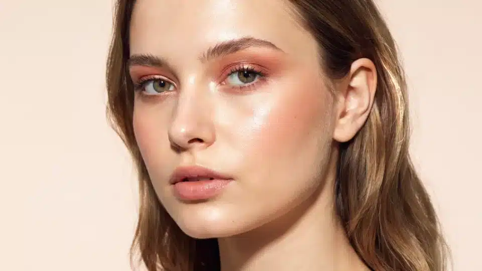 Woman wearing rose gold eyeshadow with a subtle metallic finish and soft natural makeup.