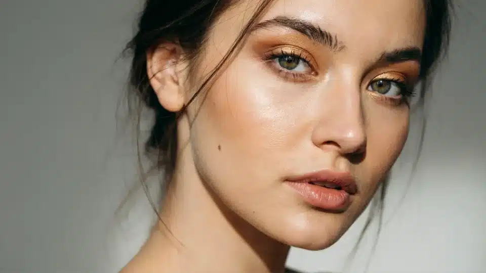 Woman wearing shimmering gold eyeshadow with a soft luminous finish that brightens brown eyes.