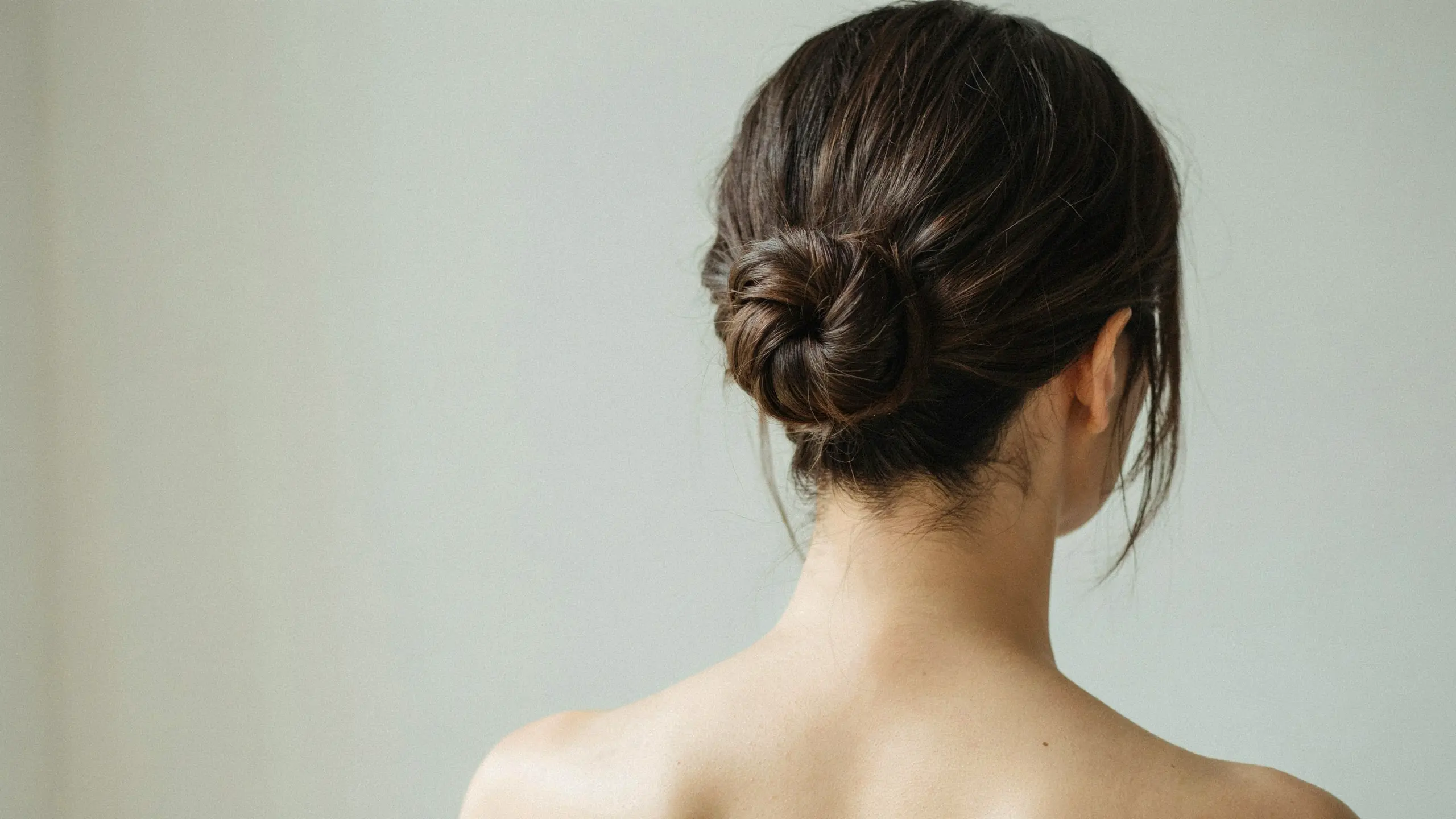 Short hair arranged into a compact low bun updo with loose face-framing strands