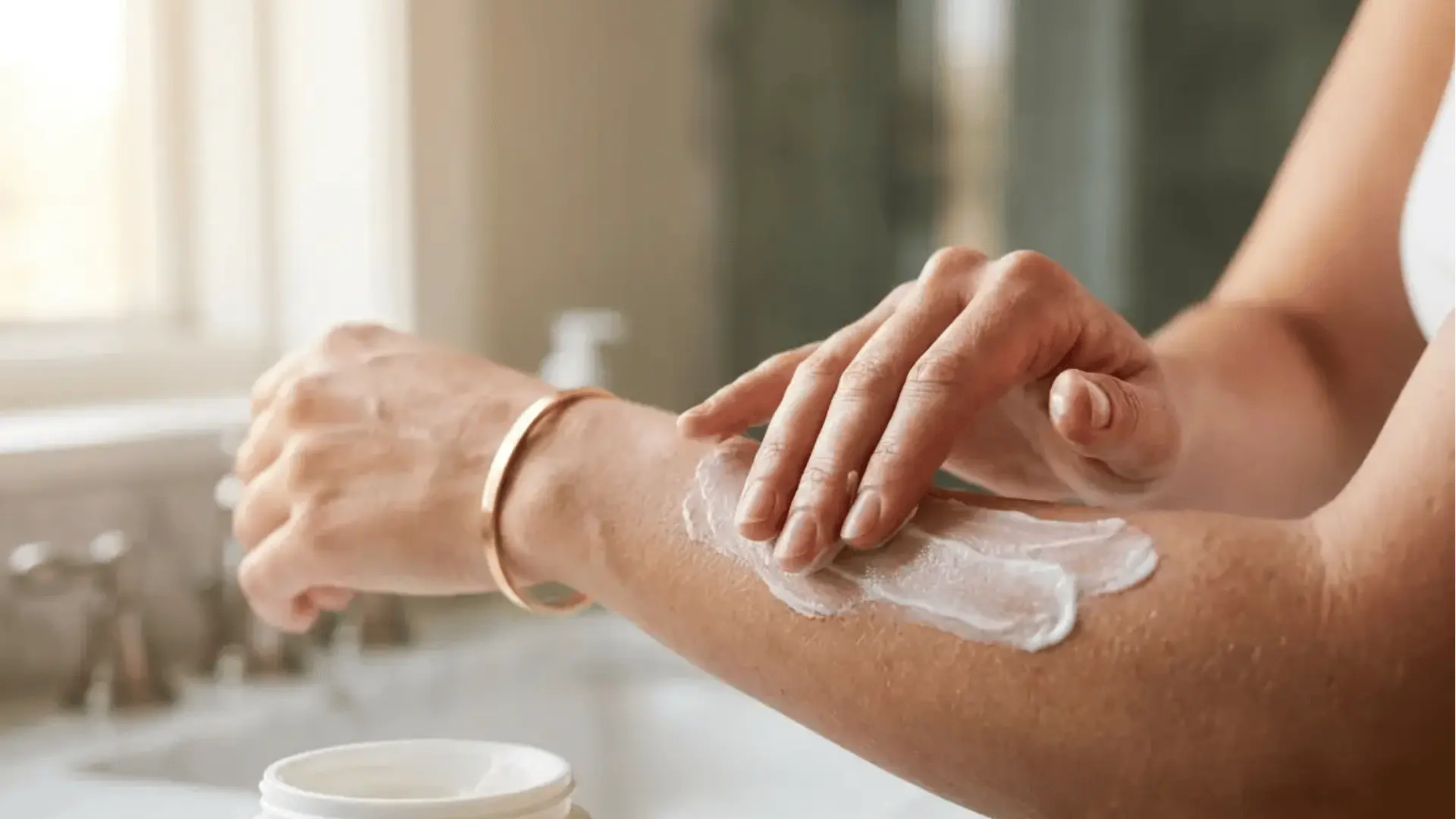 Woman applying Crepe Erase moisturizer cream on her arm in a bright bathroom setting