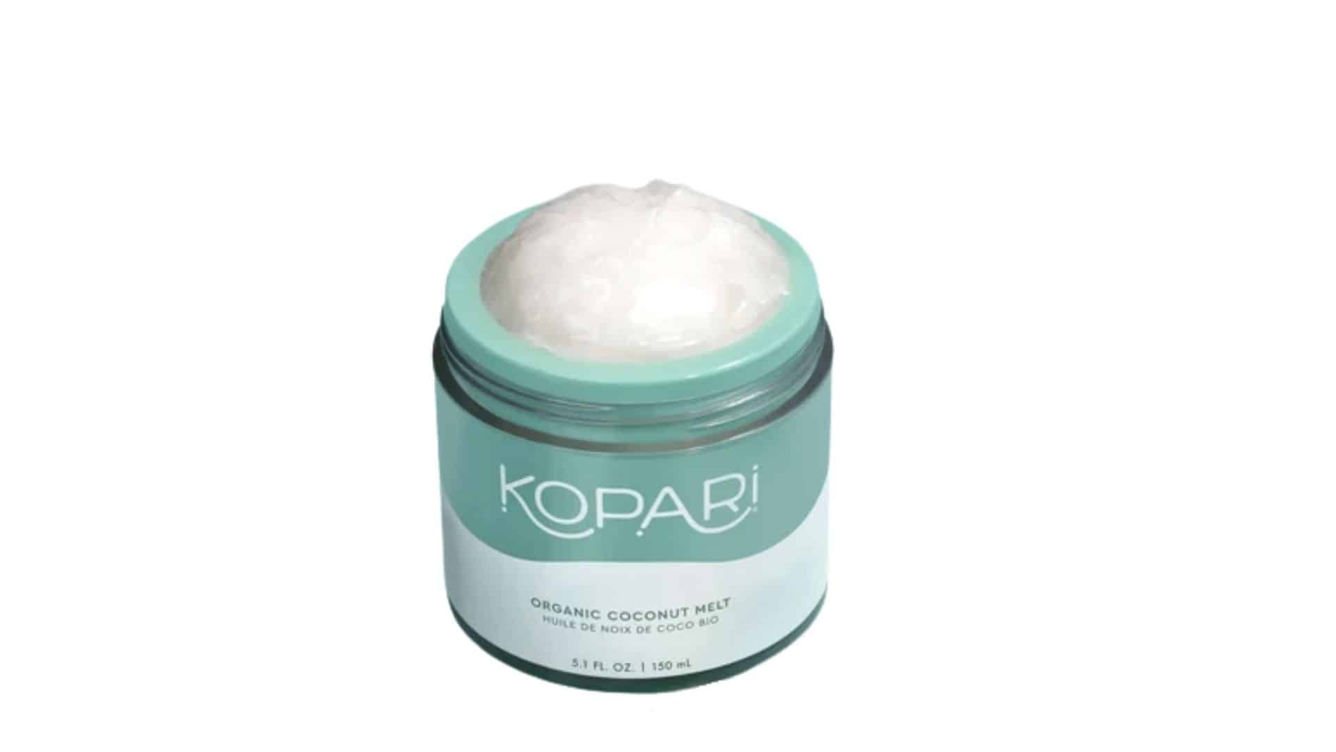 An open jar of Kopari Organic Coconut Melt with coconut balm and a smear on a light teal background.