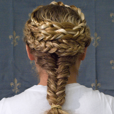 Back view of a woman wearing a detailed braided hairstyle with a crown braid and fishtail braid.