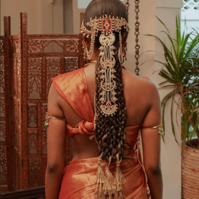 Back view of a woman wearing a traditional South Asian braid decorated with gold hair ornaments and jewelry.