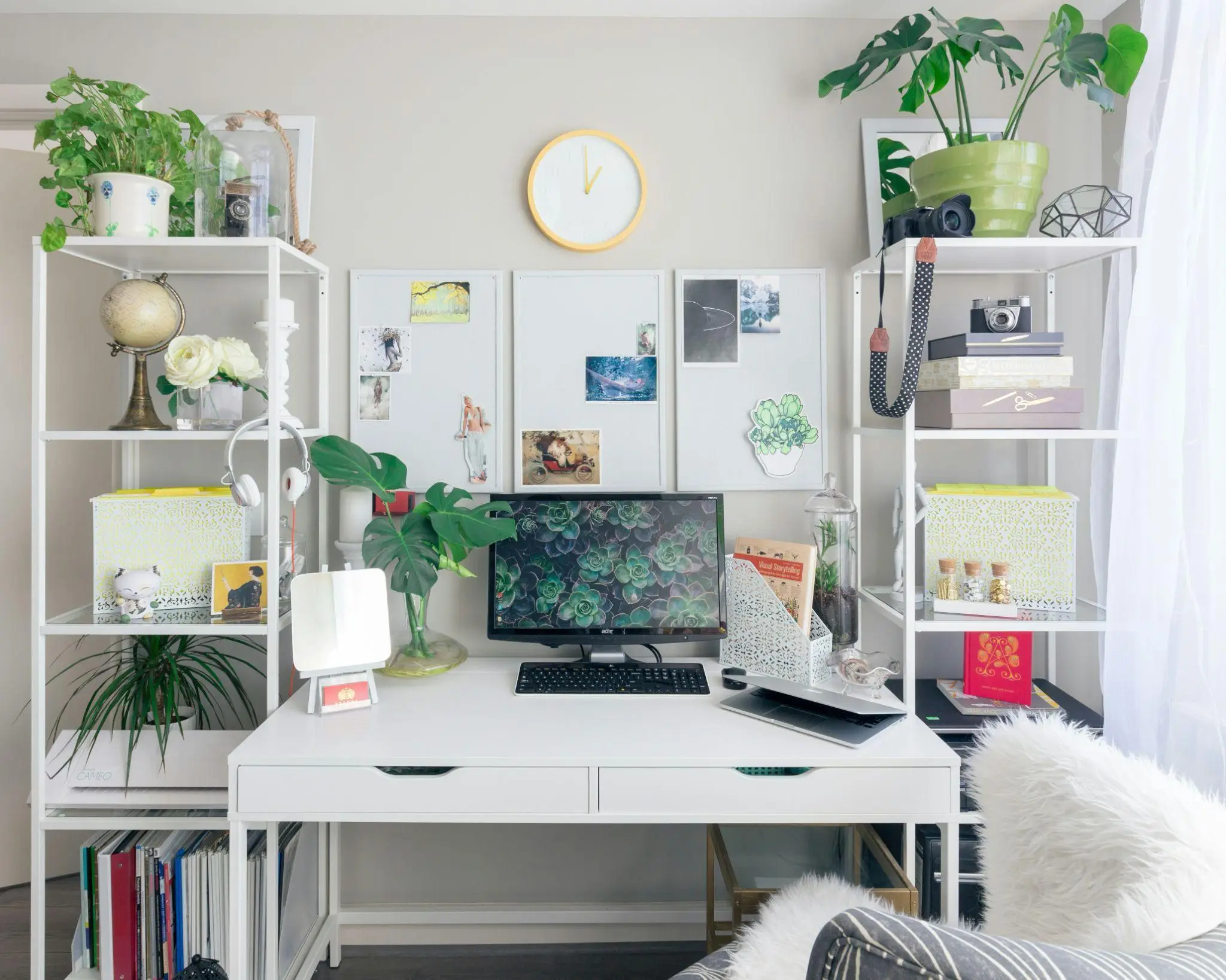 Organized home office with white desk, plants, and computer under bright natural light