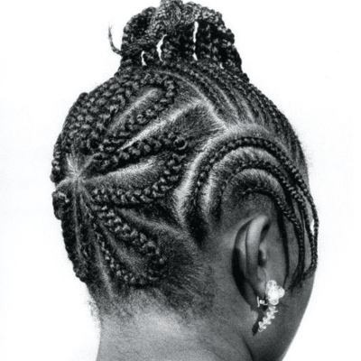 Black and white image showing intricate braided cornrow hairstyle patterns with a detailed updo.