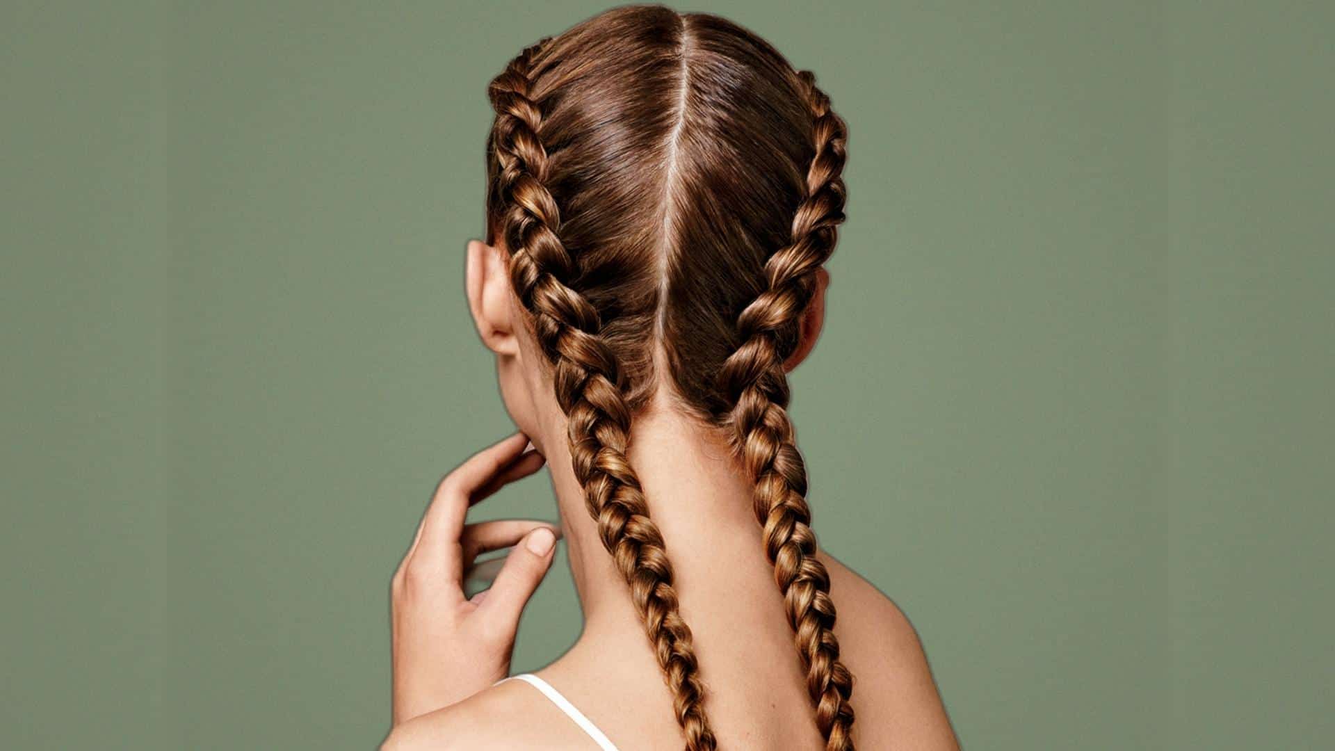 Braided pigtail hairstyle with twisted rope braids against a sage green background.