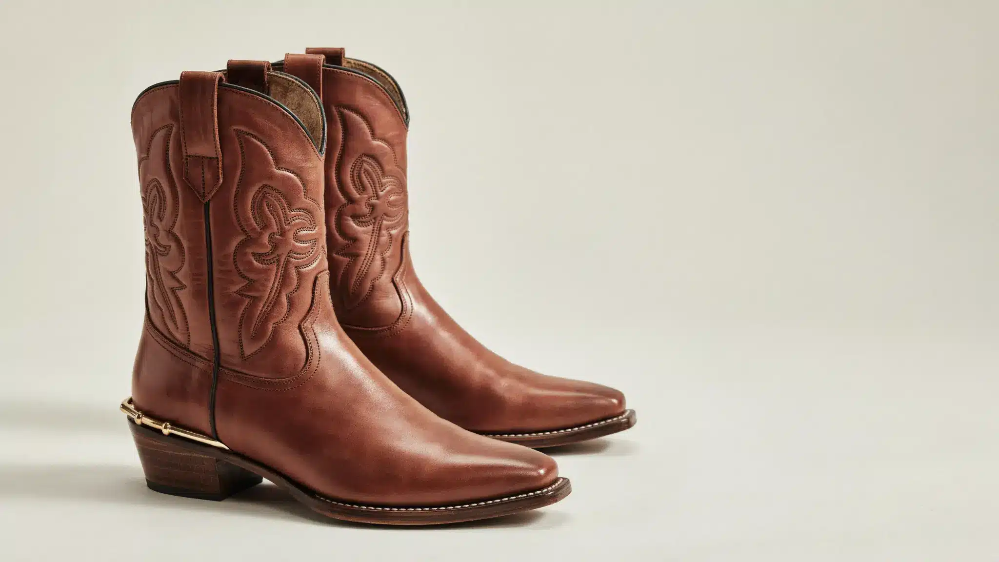 Brown leather western dress boots with embroidered patterns and pointed toes displayed on a clean neutral background