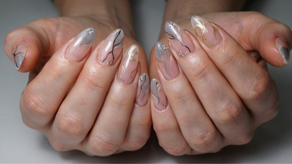 Almond nails featuring detailed patterns with marble effects, fine lines, and glossy artistic manicure details