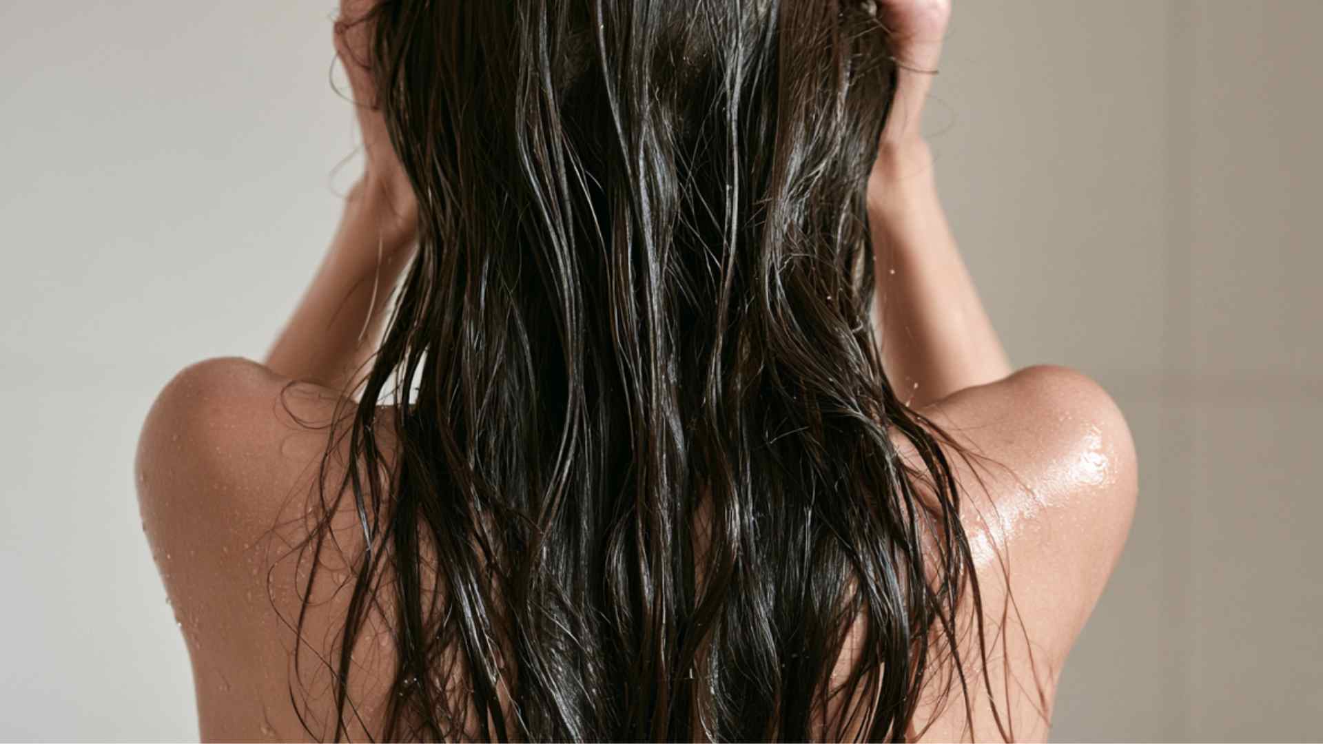 Hands gently squeezing excess water from freshly washed damp hair before applying rice water