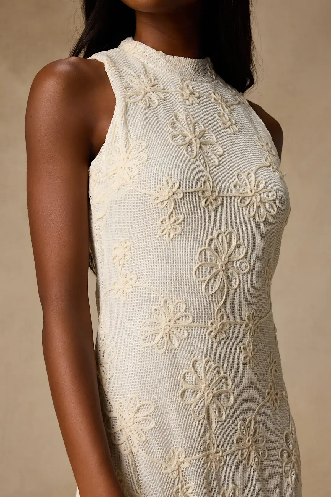 Sleeveless cream dress with floral embroidery in close-up studio shot