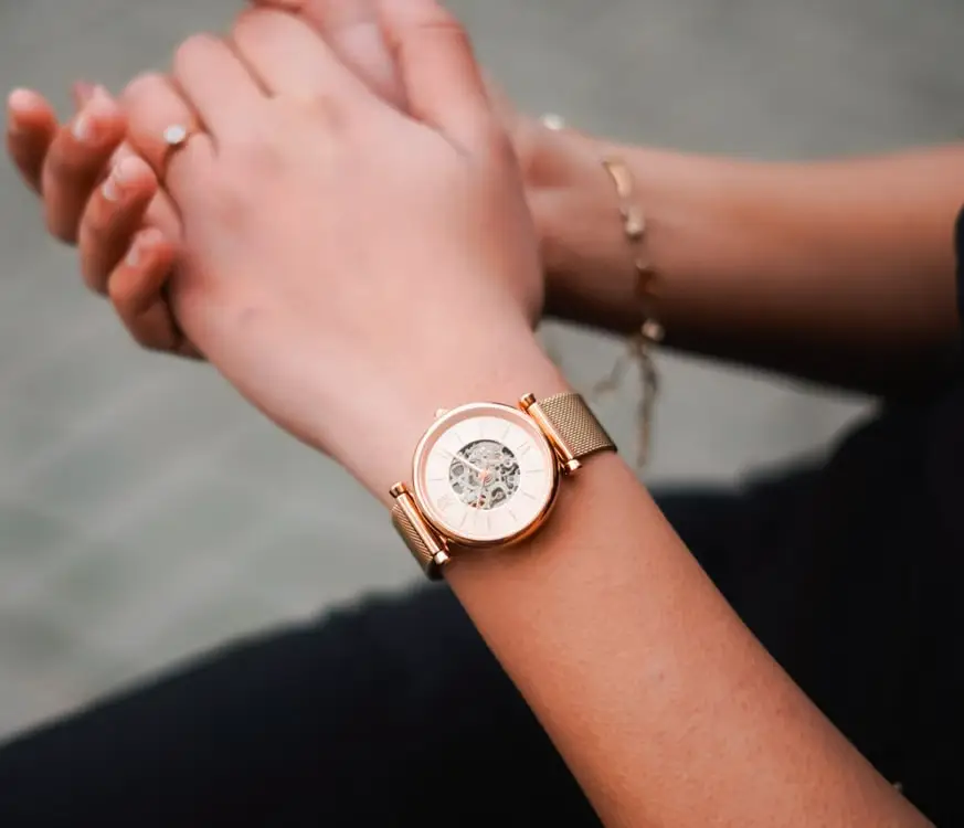 Close-up of a rose gold wristwatch with visible mechanical gears on a wrist