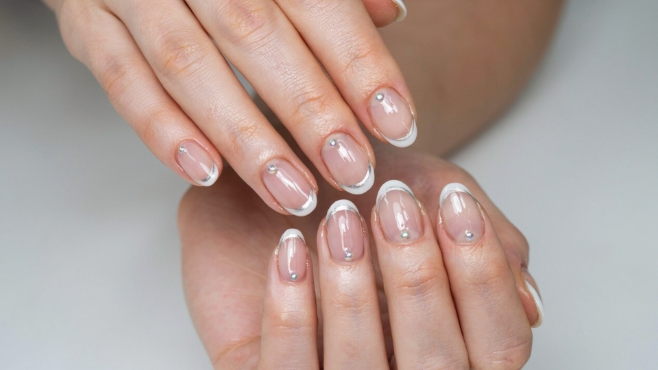 Close up hands showing rounded nails with tiny French edges and clean minimalist nail art