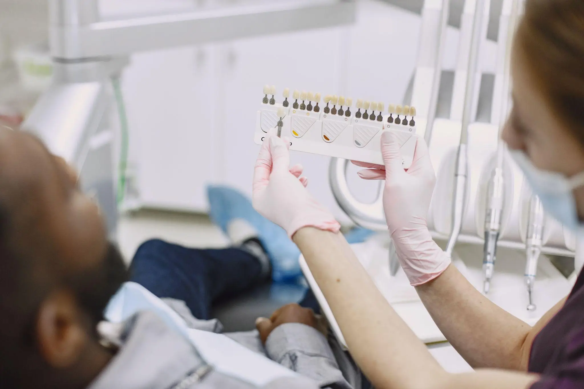 Dentist showing patient a tooth color chart in a bright clinic setting