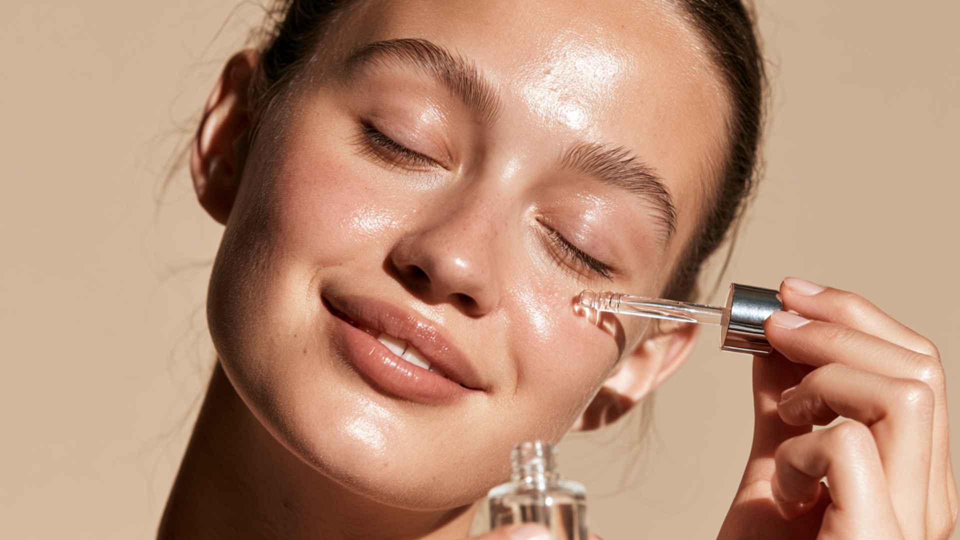 Person applying jojoba oil skincare serum with a dropper on glowing facial skin during a natural beauty routine