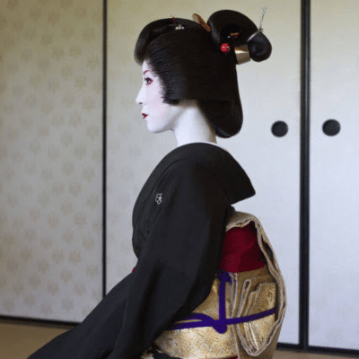 Traditional Japanese geisha wearing an elaborate updo hairstyle with ornate hair accessories and formal kimono.