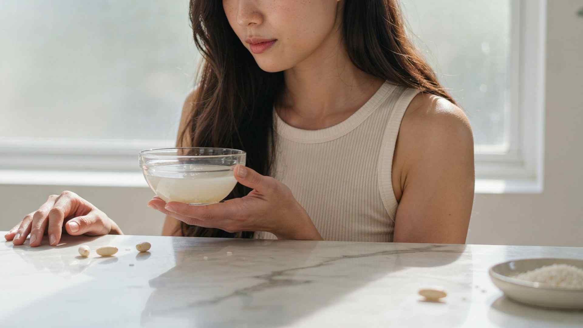 Woman holding rice water beside healthy hair in a bathroom
