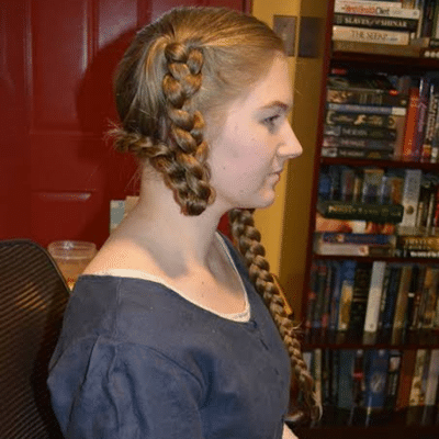 Woman wearing a traditional braided hairstyle with a long braid, folded from one side.