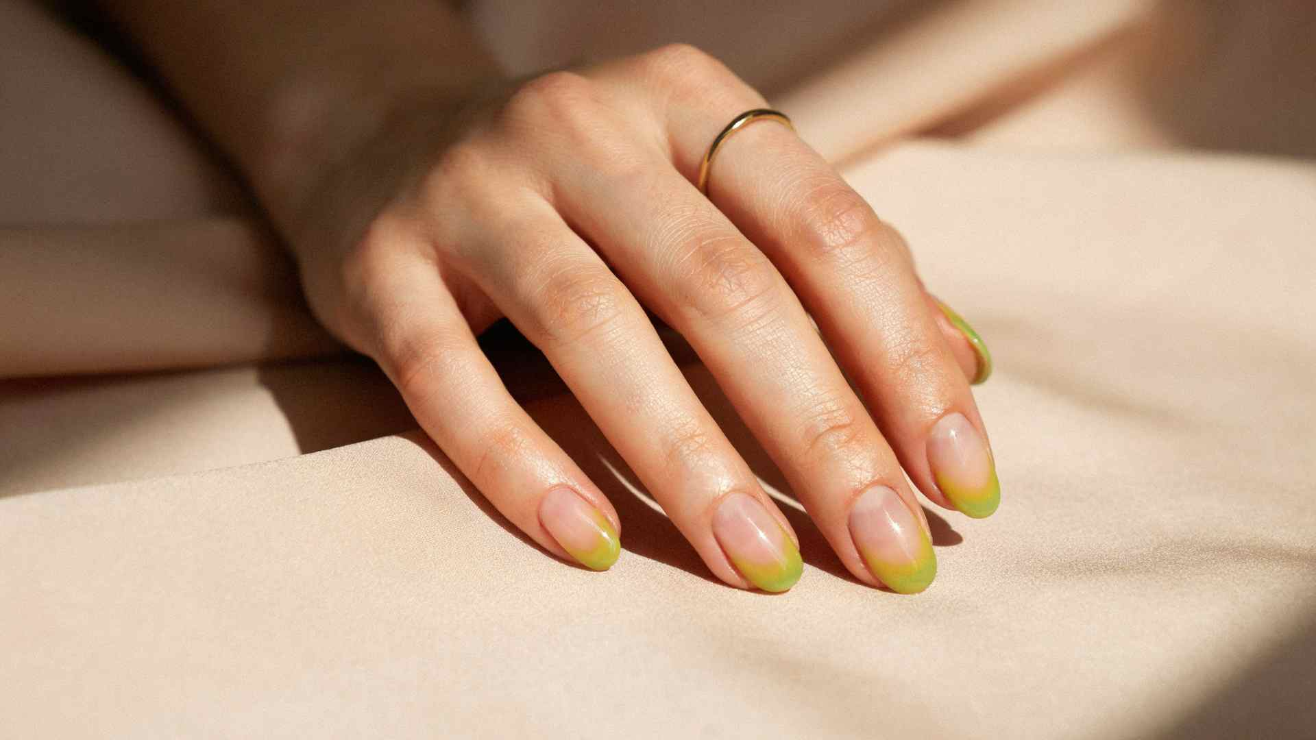 Lime and yellow aura nails with hazy citron centers and green edges over a translucent base on glossy almond nails