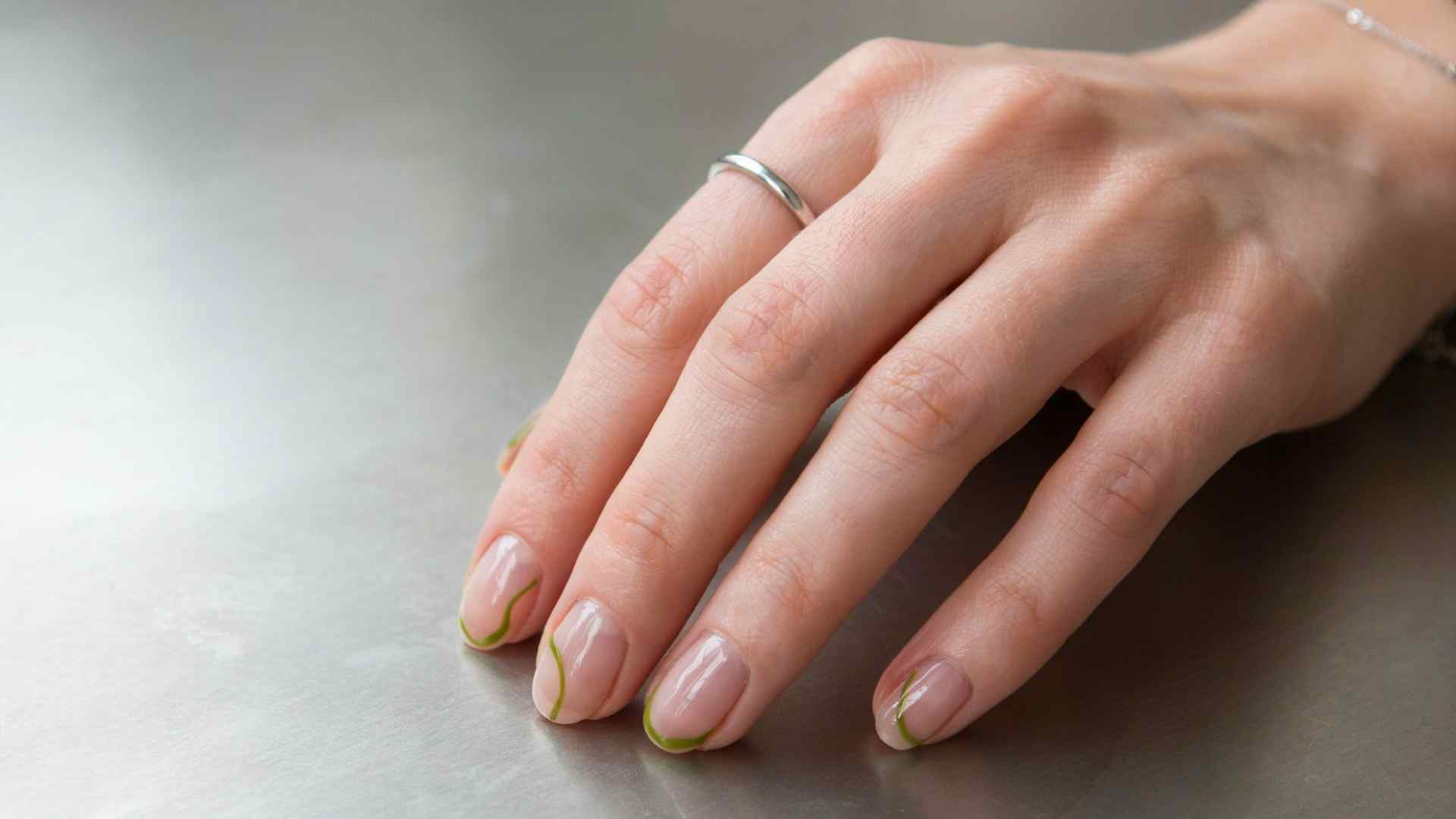 Neon green negative space lines curve around short natural nails with a sheer pink base and polished summer finish