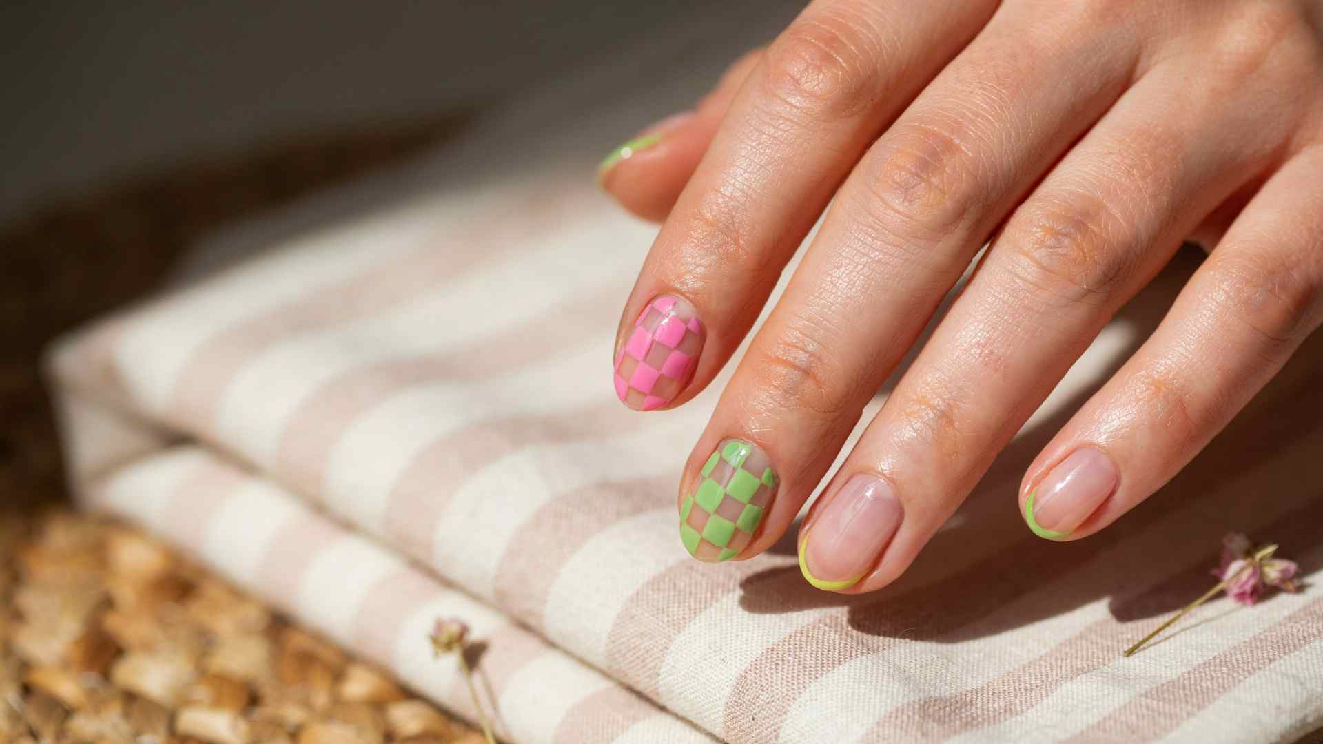 Neon pink and lime checkerboard accent nails paired with a sheer manicure and softly irregular hand painted squares