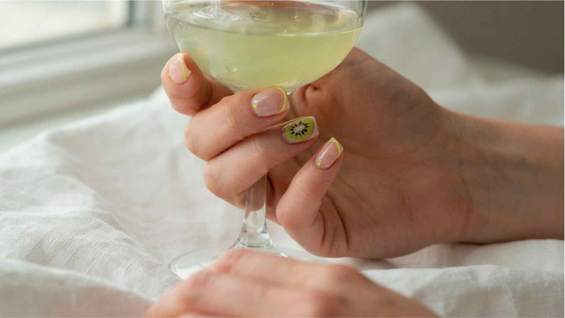 Tiny kiwi fruit details decorate sheer short nails with a lime green base for a playful summer manicure