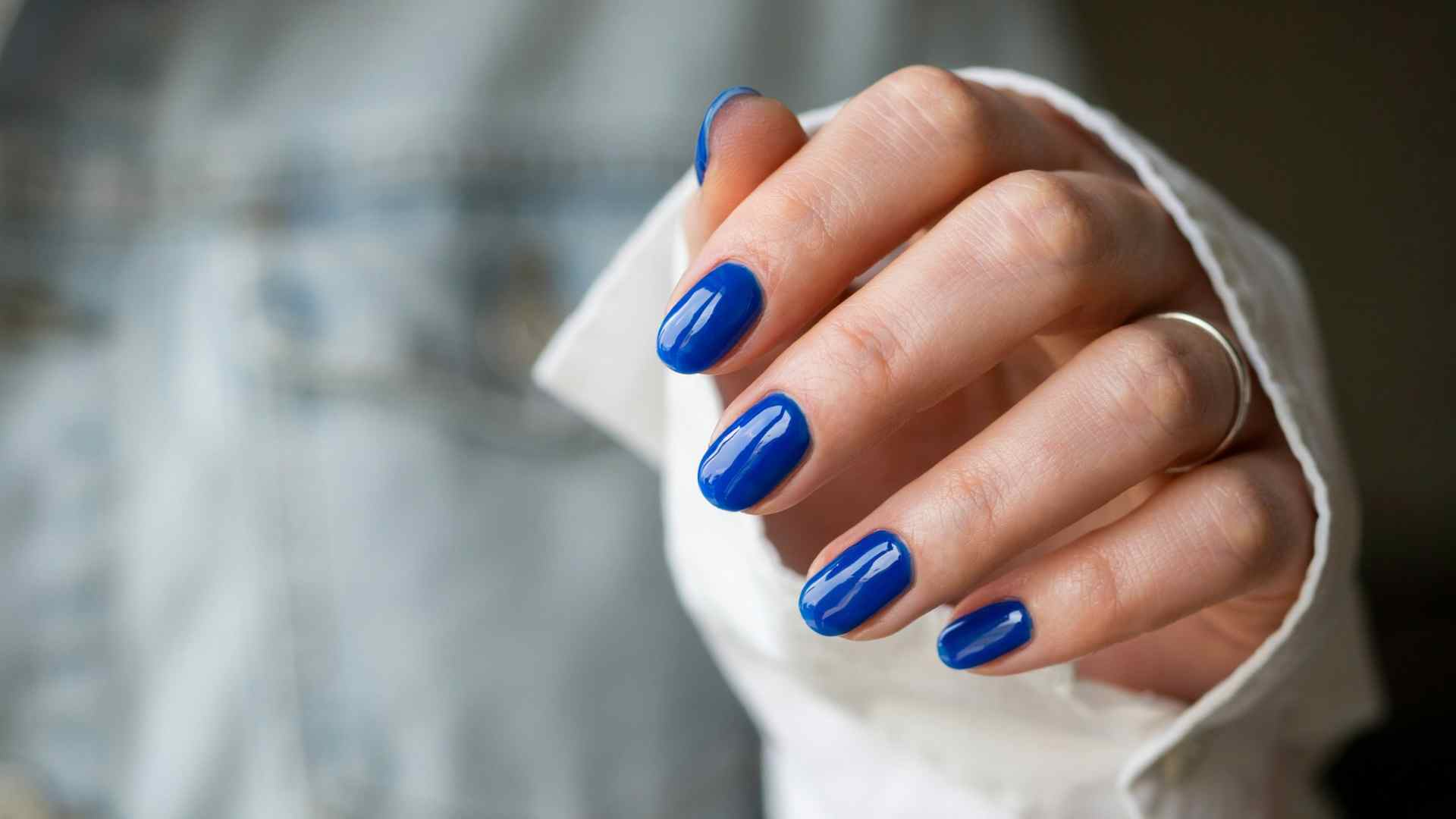 Electric blue glossy nails with a bold solid summer manicure finish on short rounded nails