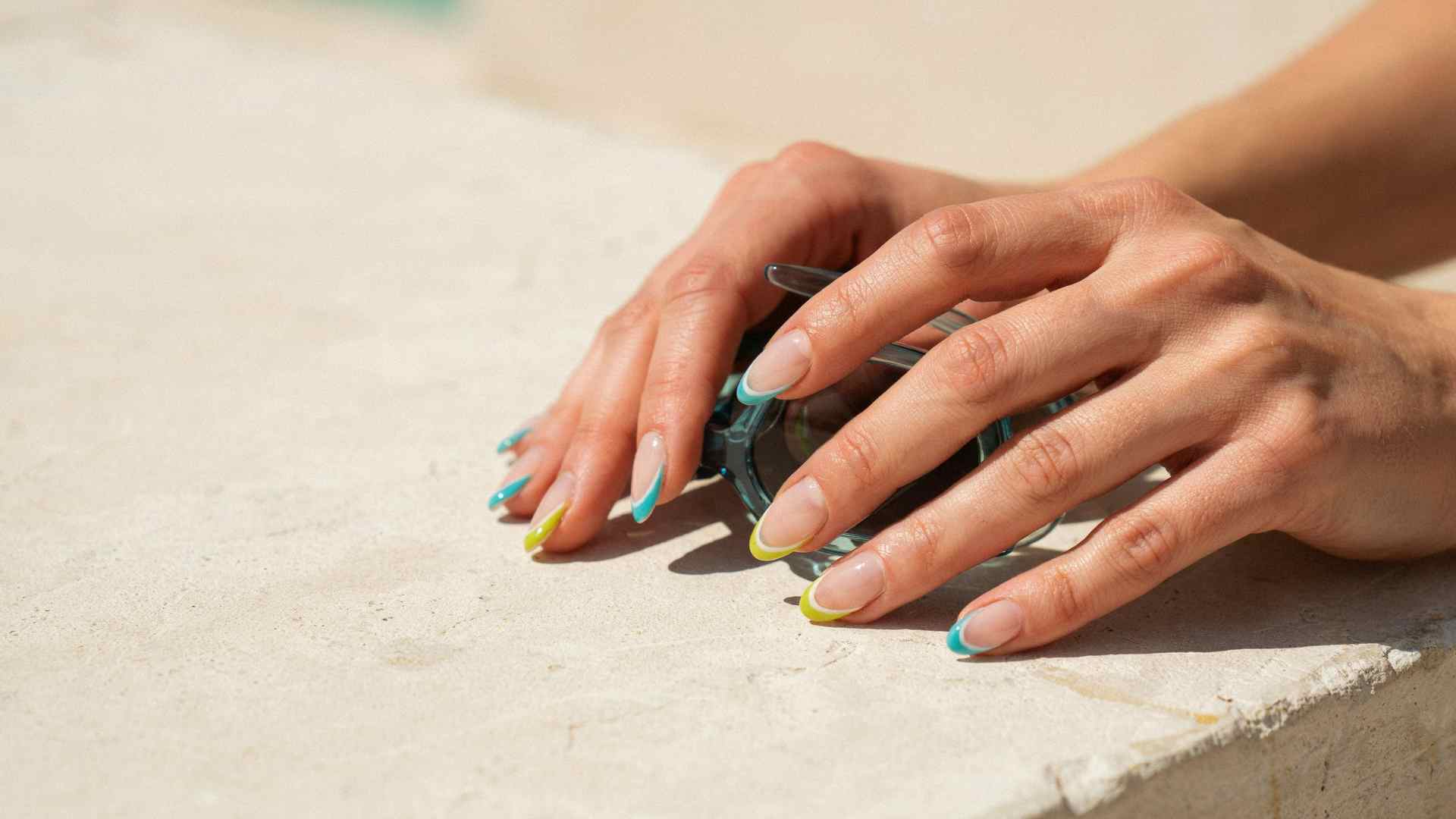Turquoise and lime French tips sweep across medium coffin nails with a sheer base and crisp summer sunlight