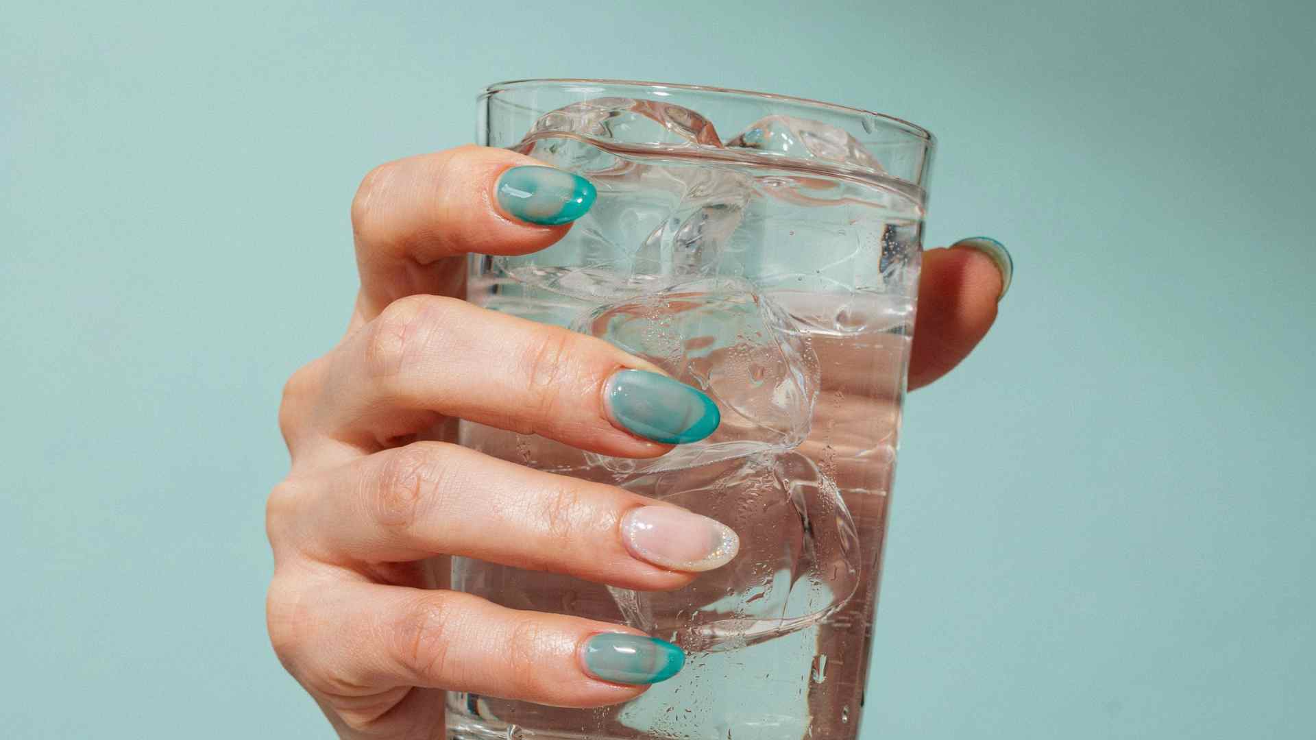 Blue and teal jelly polish layers across long oval nails with translucent color and watery reflections