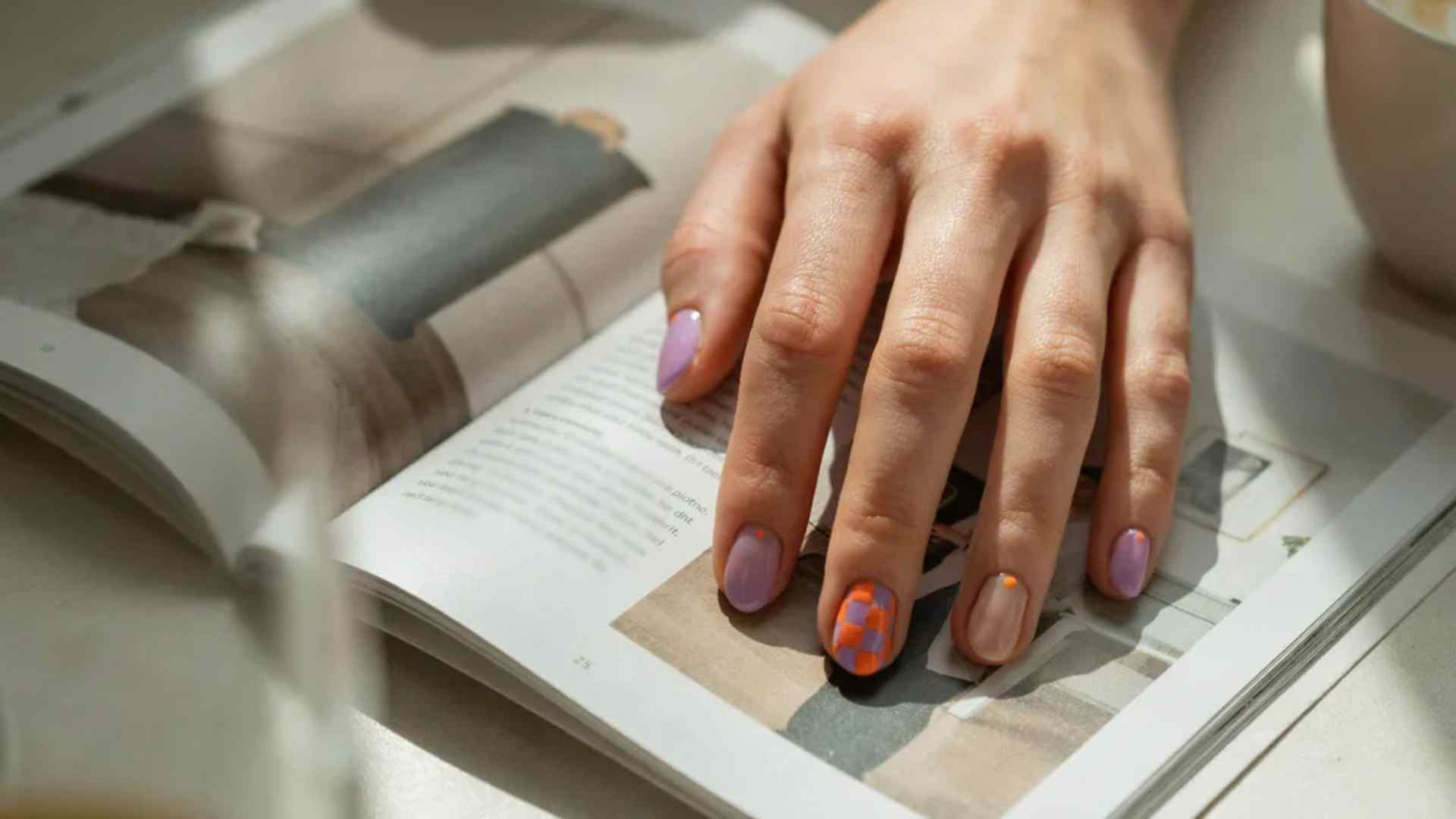 Purple and orange checkerboard nail art covers selected short squoval nails beside softer sheer lavender accents