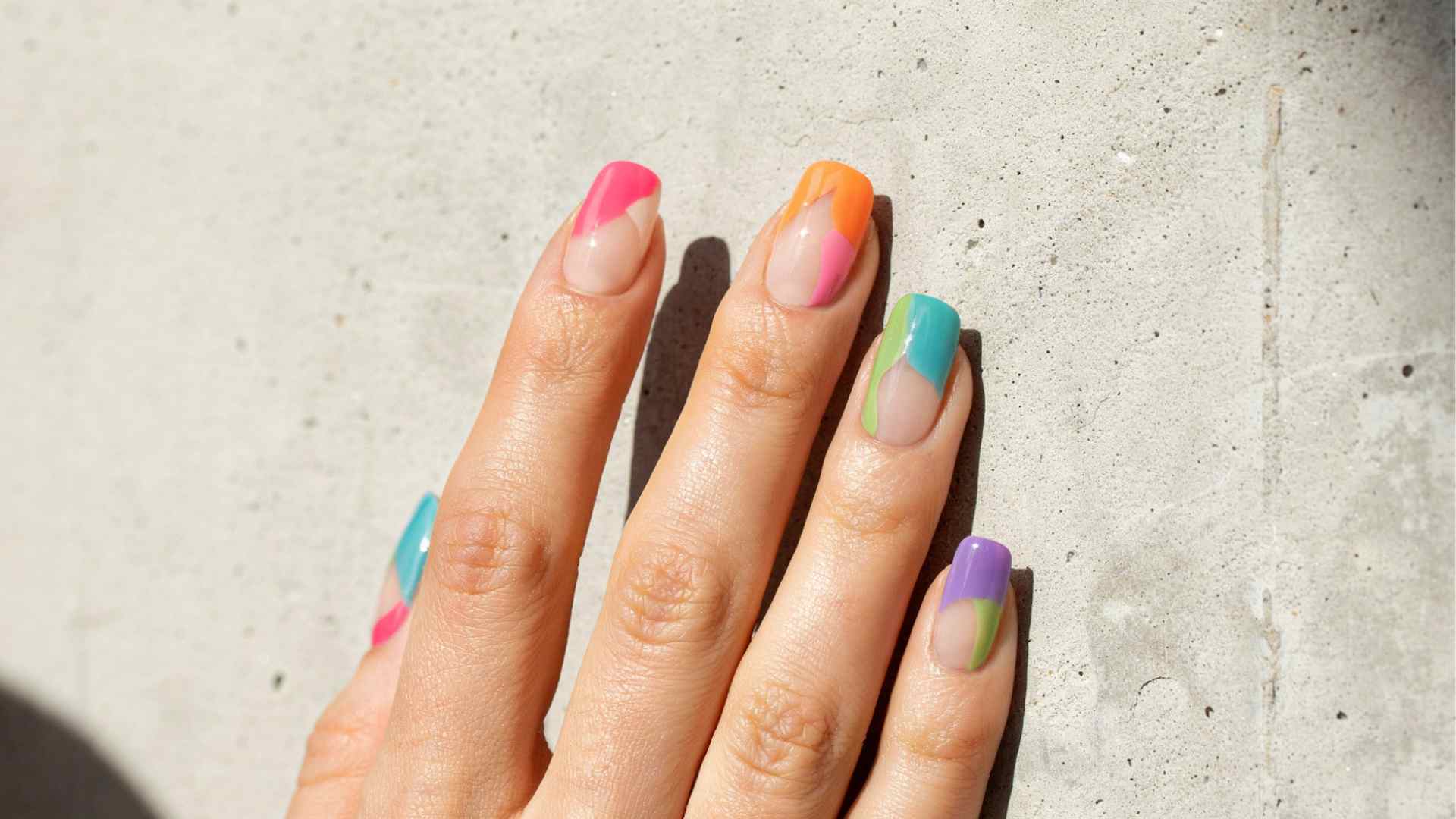 Neon color block nails divide pink orange lime turquoise and yellow across long tapered square tips with sheer sections