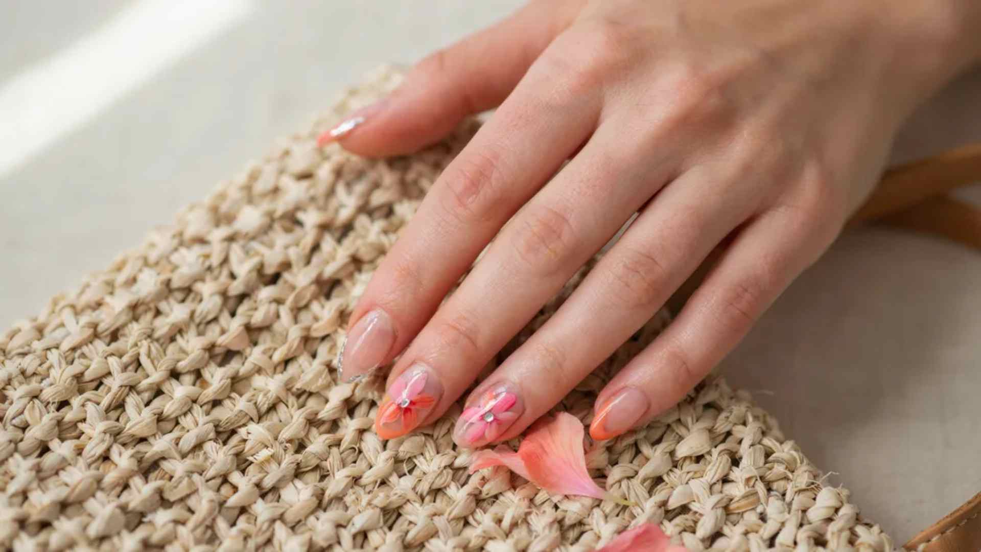 Coral and pink hibiscus flowers pair with small chrome details across long ballerina nails on a sheer peach base