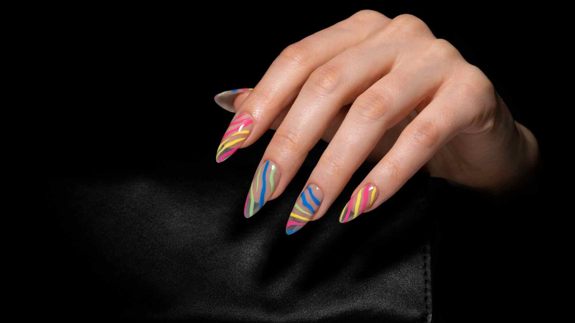 Neon zebra stripes in pink yellow lime and blue sweep across long stiletto nails with a sheer smoky nude base