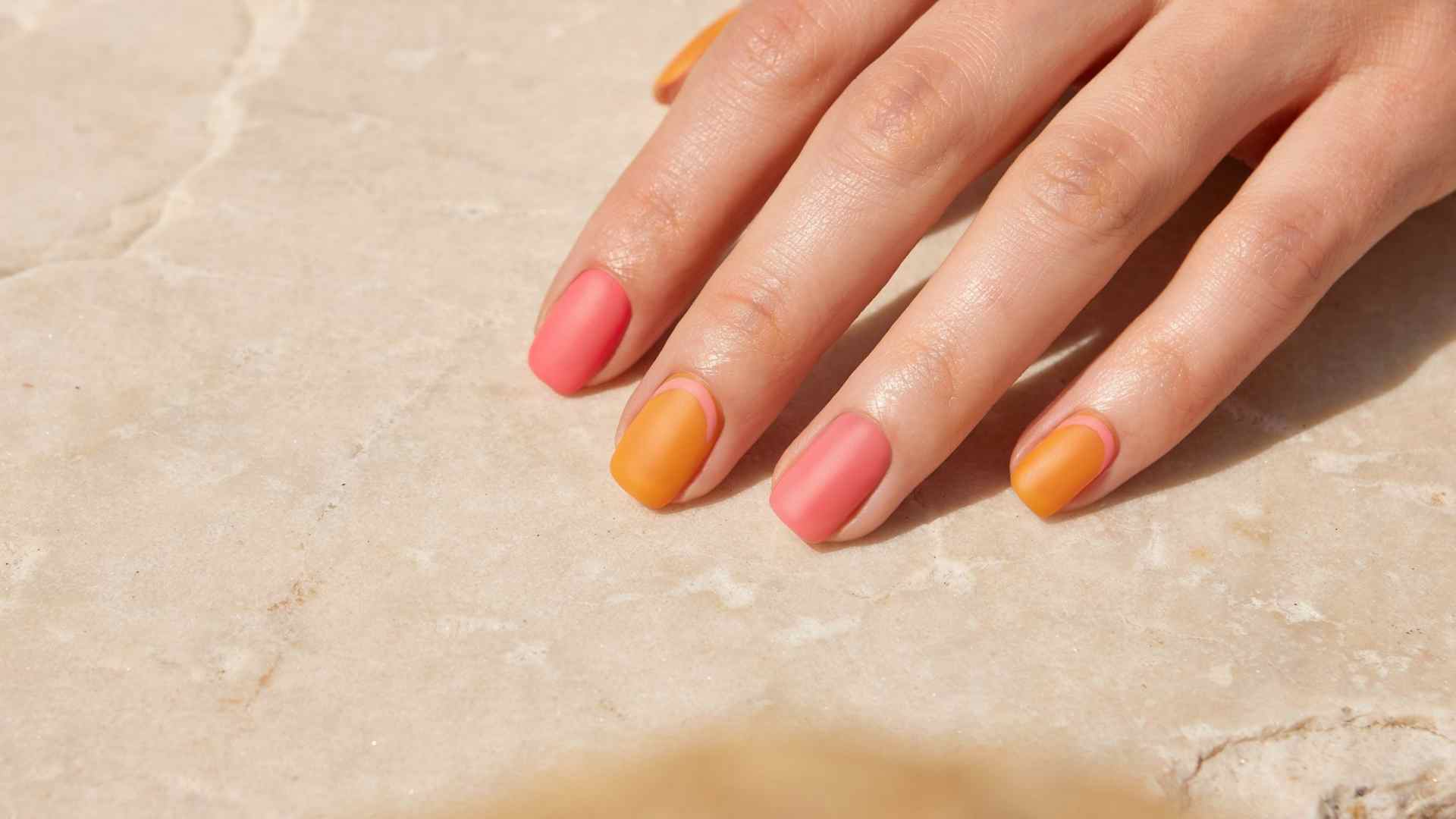 Matte pink and orange polish covers extra short square natural nails with a soft velvet finish and simple summer styling