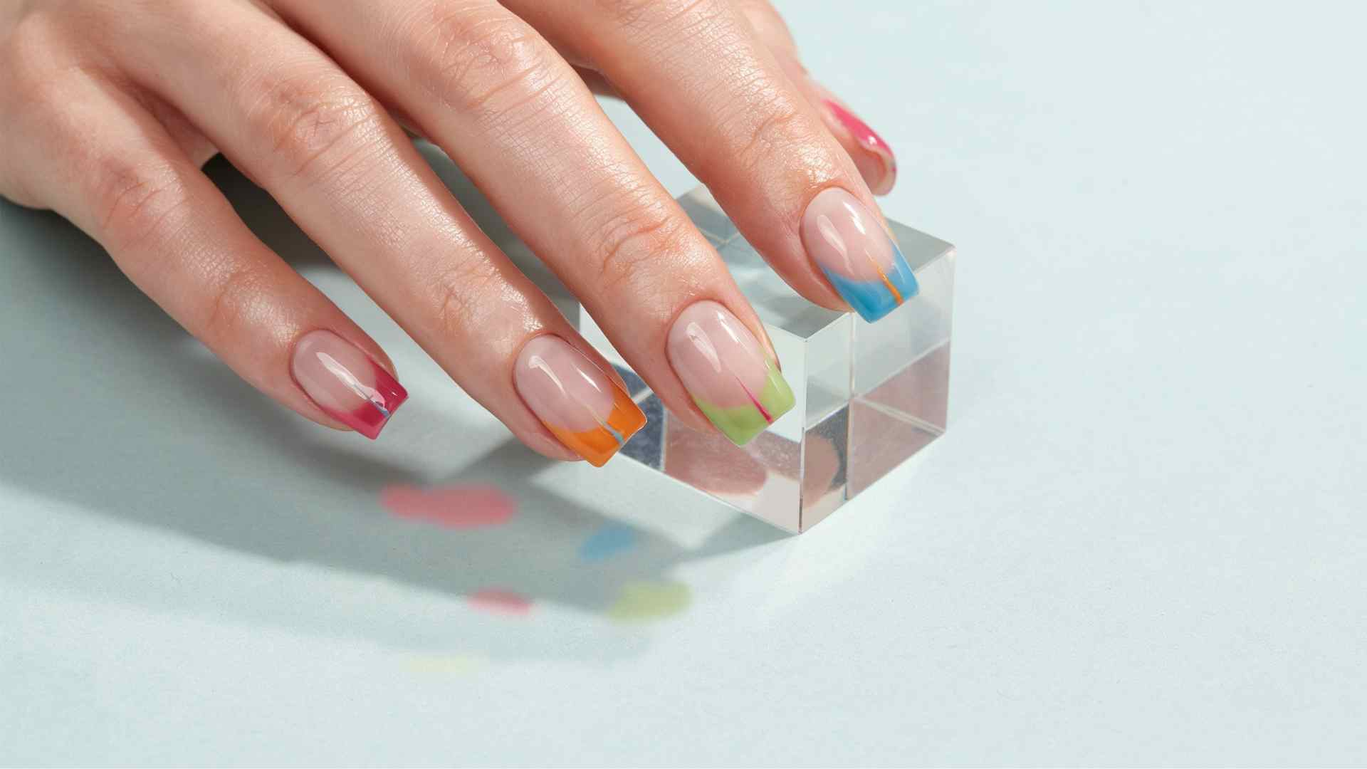 Neon jelly diagonal French tips in pink orange lime and blue cross medium tapered square nails with a sheer base