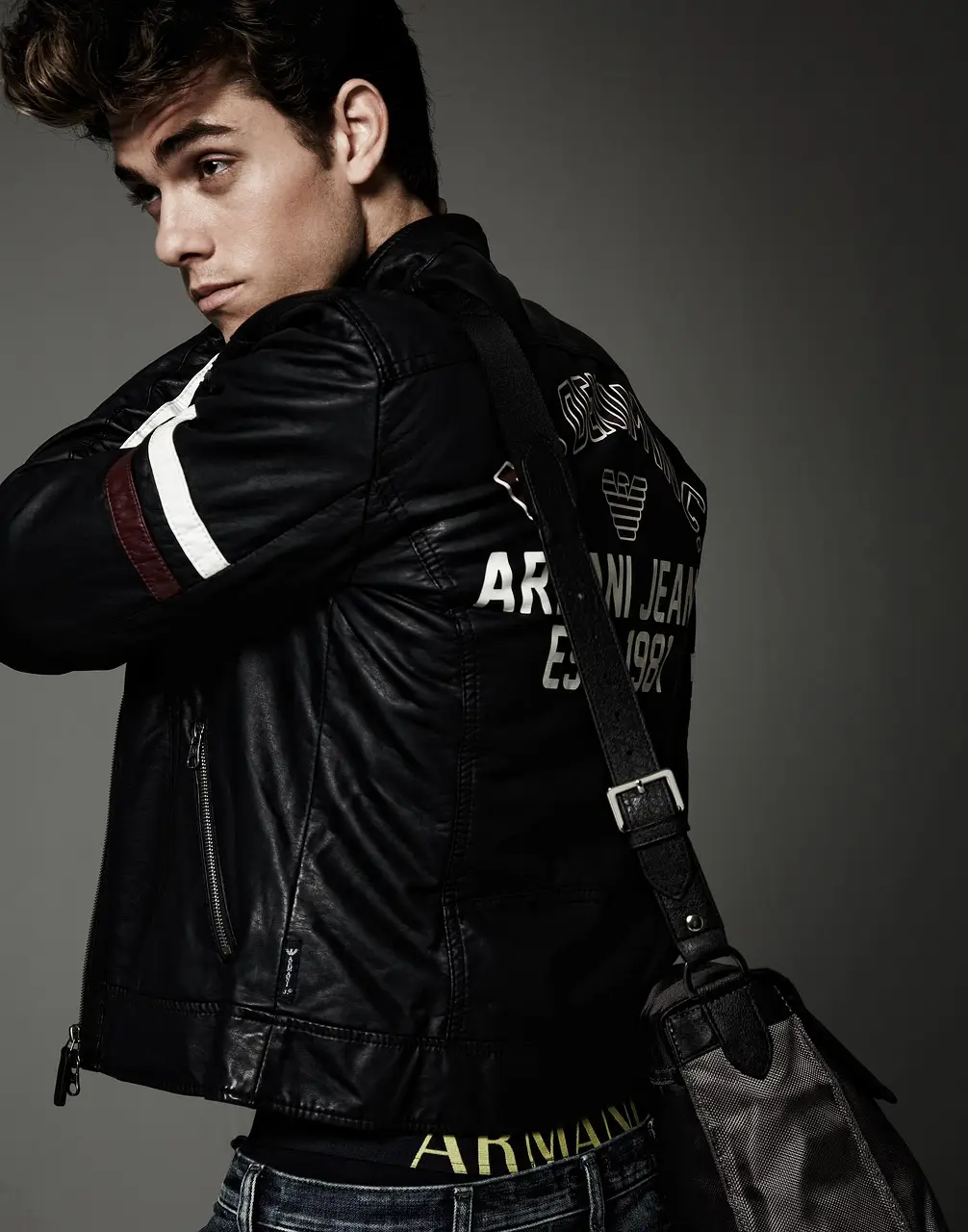 Man in a leather jacket with shoulder bag in a studio setting
