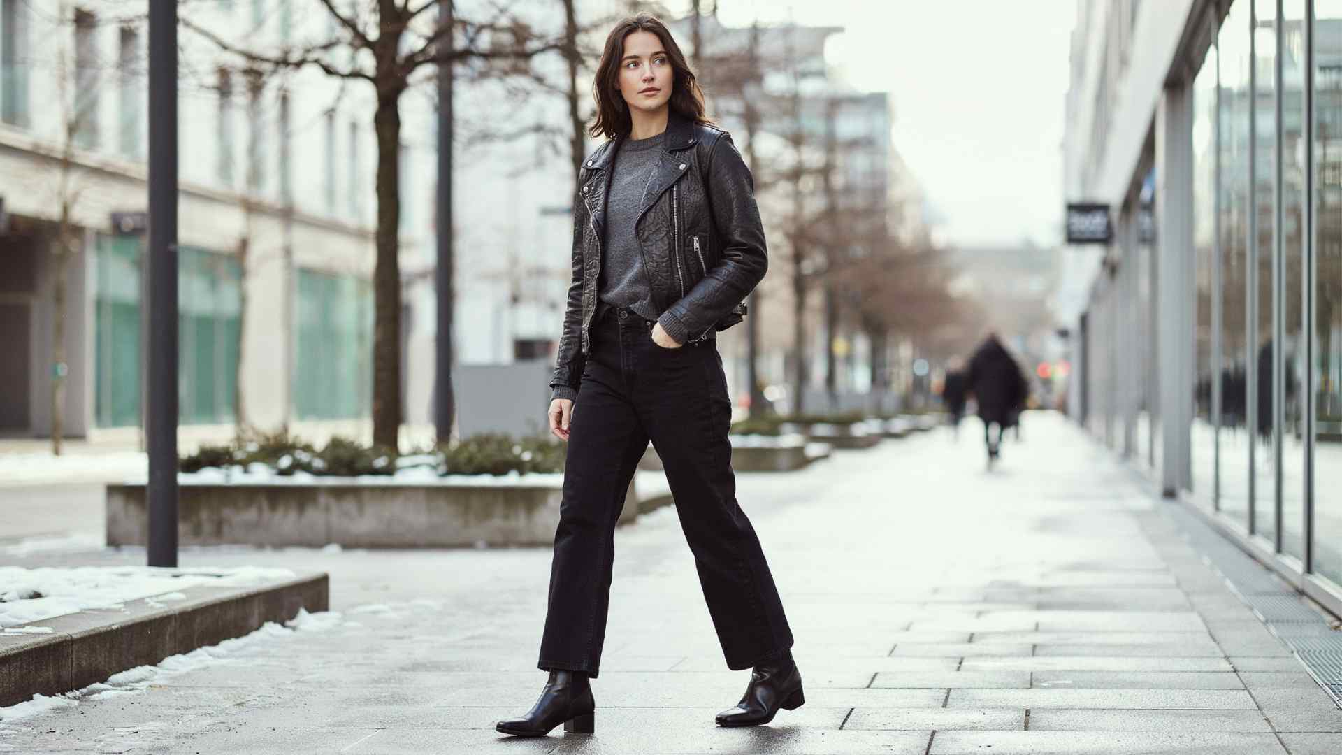 Young woman in black wide leg jeans with a leather jacket and neutral sweater