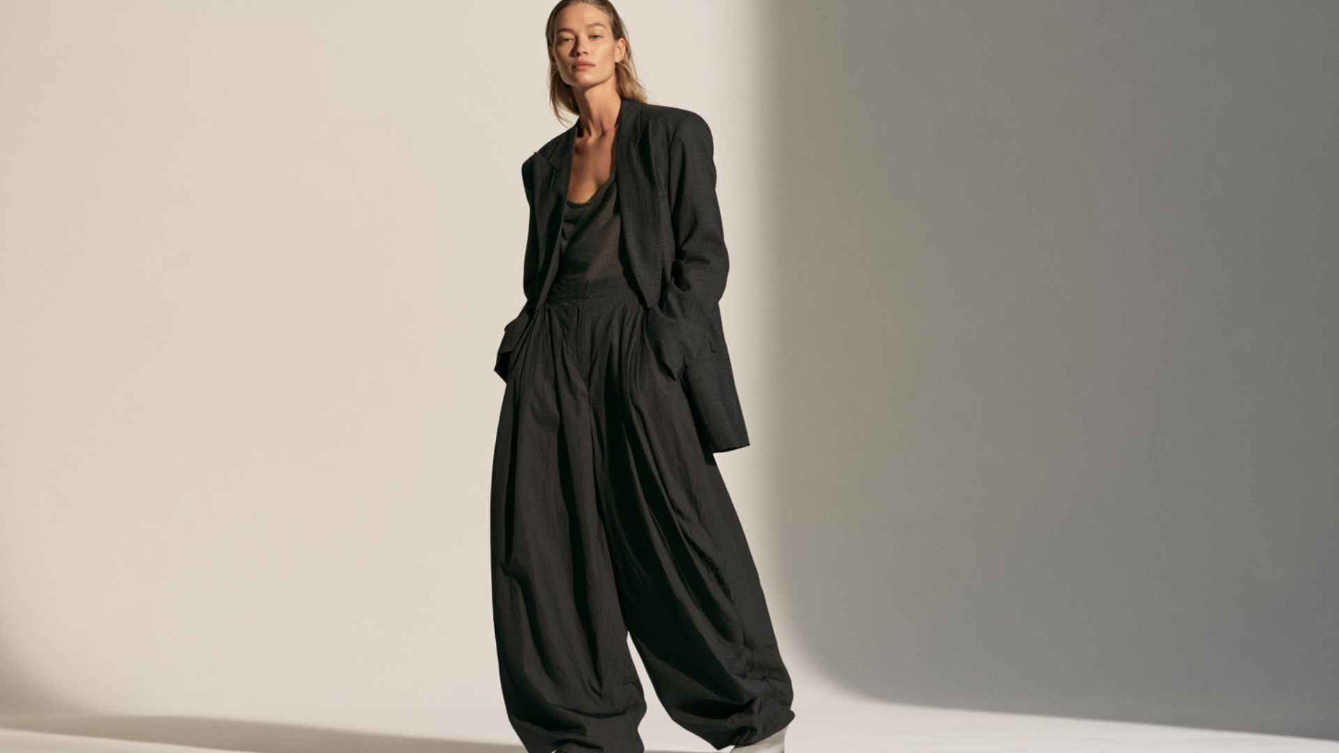 Woman styling relaxed parachute pants with a structured blazer and fitted top for a smart-casual look.