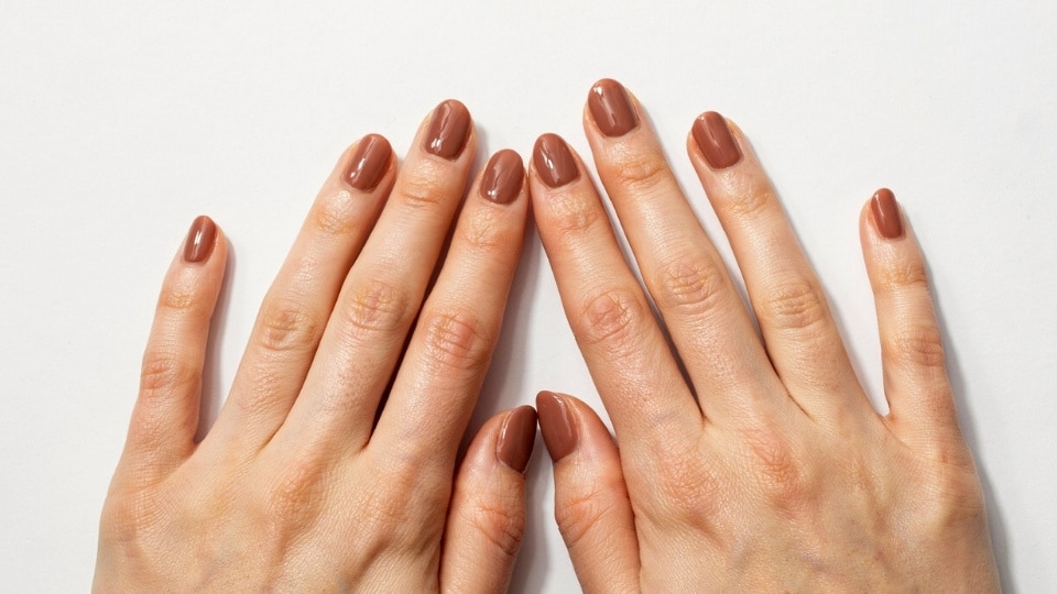hands featuring chocolate brown nails with a warm glossy finish