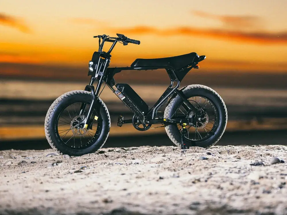 Electric bike with fat tires on sandy beach during vibrant sunset