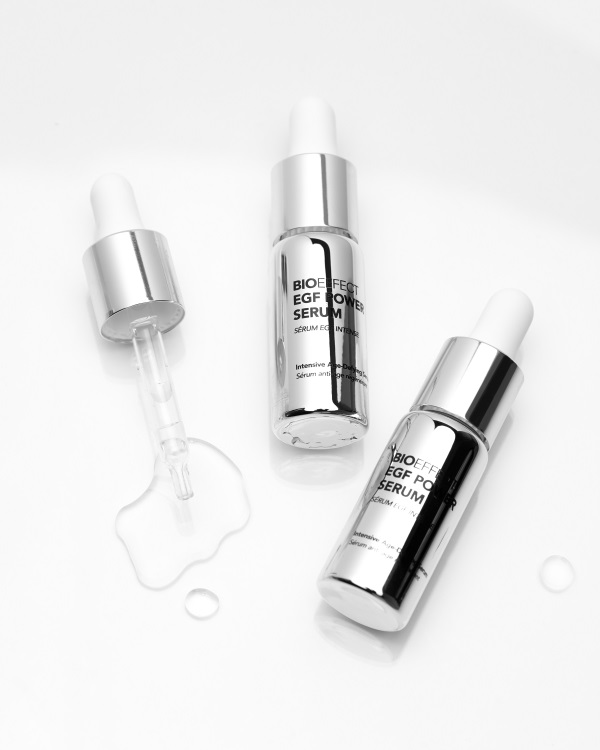 Three silver skincare serum bottles with droppers on white background