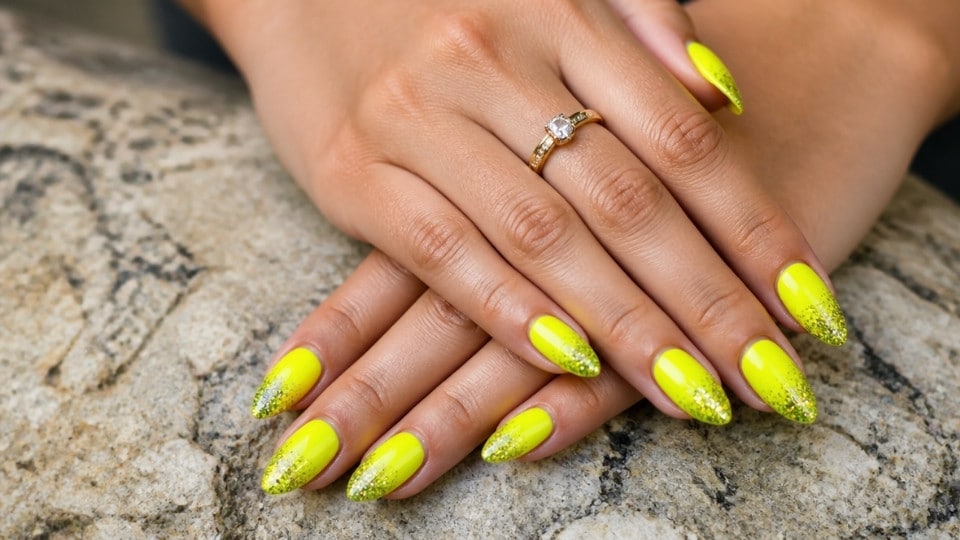 Neon yellow glitter fade nails with gold sparkle accents and a glossy gradient finish