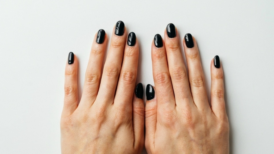 Hands showing glossy black nails with a sleek mirror shine and modern winter manicure style