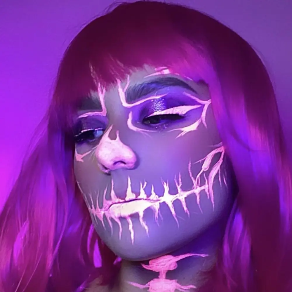 Glow in the dark skeleton makeup with a UV white base, black bone details, and a neon shadow around eyes and cheeks