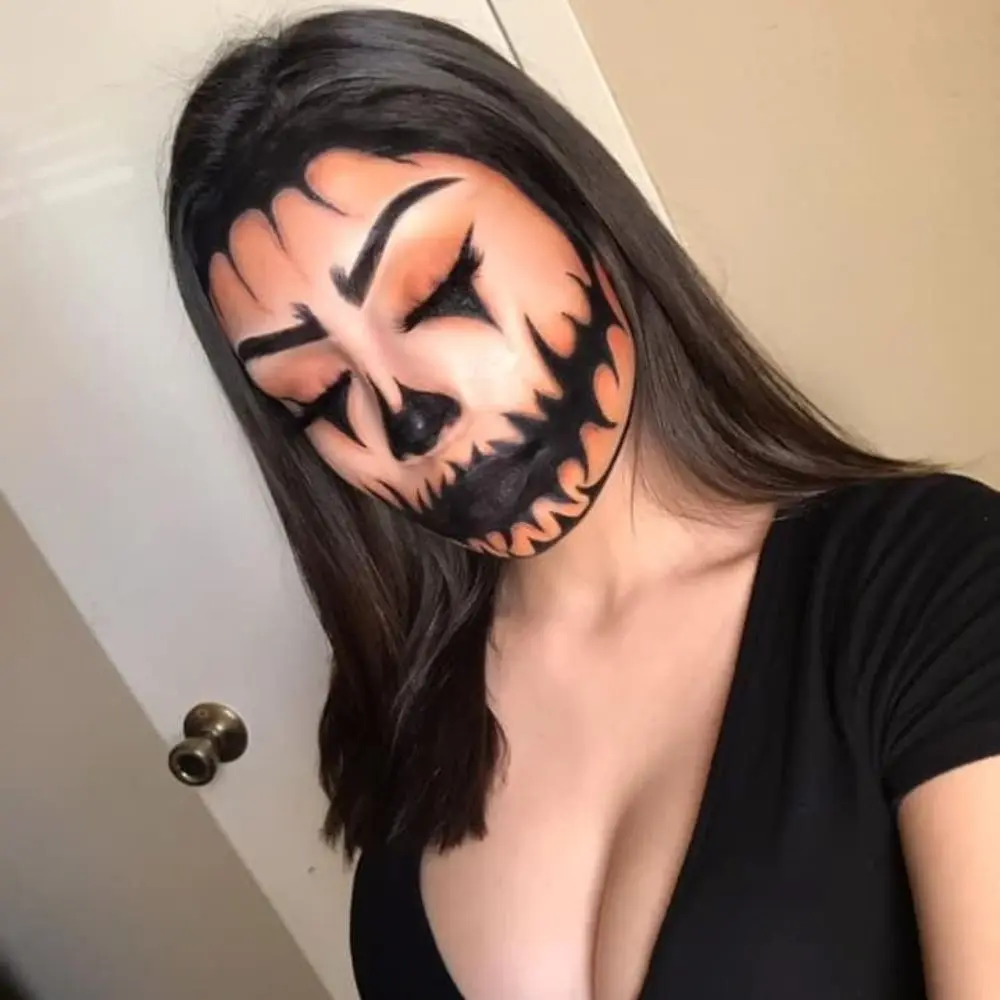 Jack o lantern makeup with orange shadow, black triangle liner details, glowing cheekbones, and soft coral lipstick