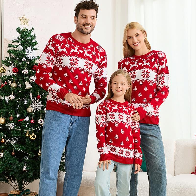 Family in matching red and white Christmas sweaters standing by decorated Christmas tree