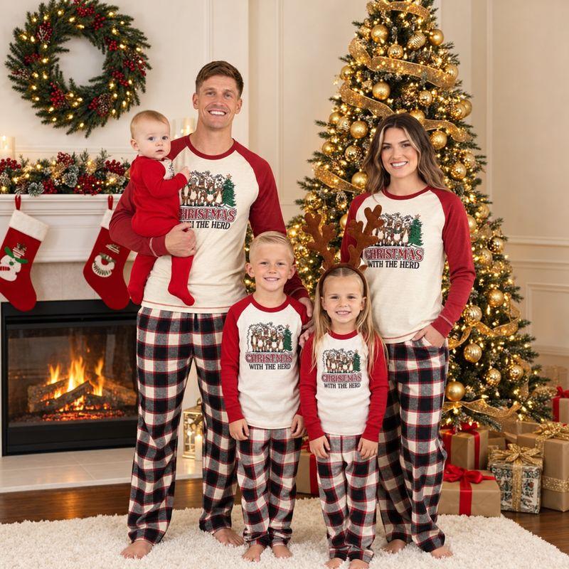 Family in matching holiday pajamas standing by decorated Christmas tree and fireplace indoors