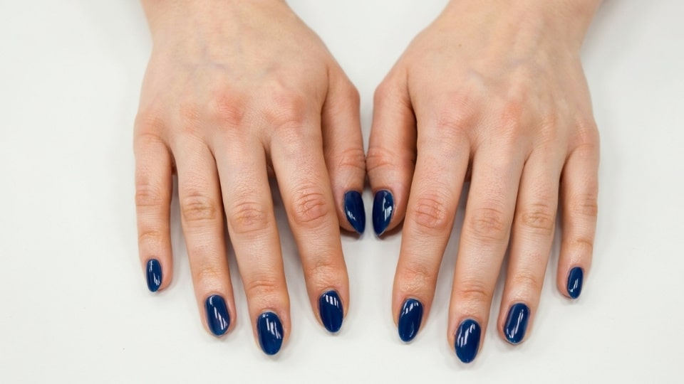 Hands displaying midnight blue nails with deep tones and a glossy sophisticated manicure finish